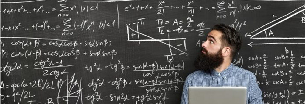 person at laptop in front of chalkboard covered in different formulas