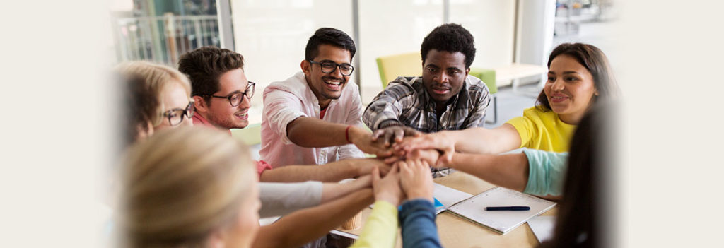 Image of Students stacking their hands on top of each other at the center of a circle