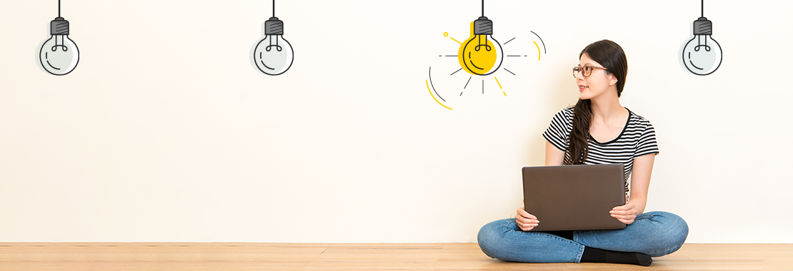 Woman on laptop sitting on the floor with lightbulb graphics above her.