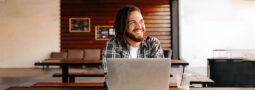 Photo of a smiling man using a laptop.