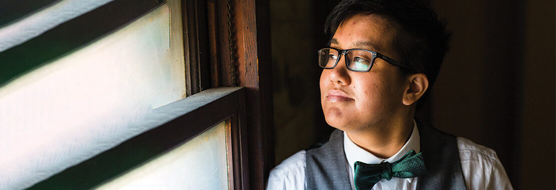 Student with bowtie smiling and gazing out window