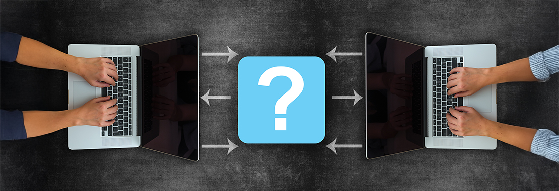 Two individuals type on laptops across from each other. Between them is a blue and white question mark symbol.