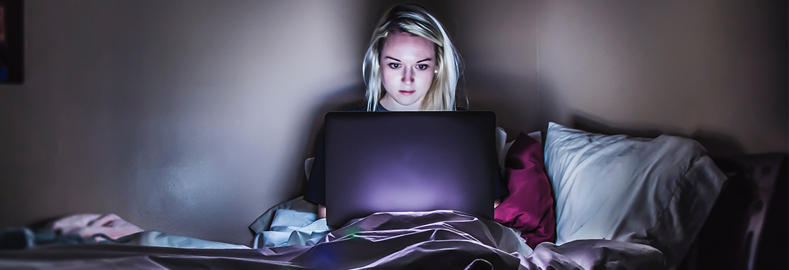 Image of a female college student studying on a laptop in the dark.