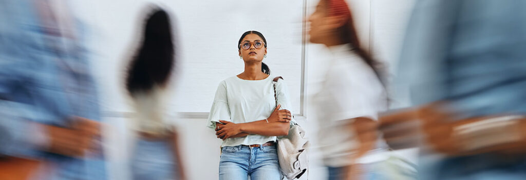 Young woman with glasses looks up between a blur of students passing by