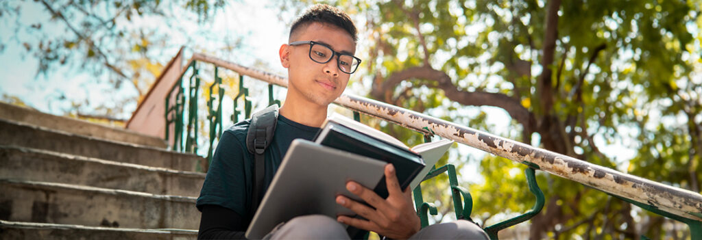 Image of a student reading a Psychology textbook while sitting on a set of stairs outdoors.