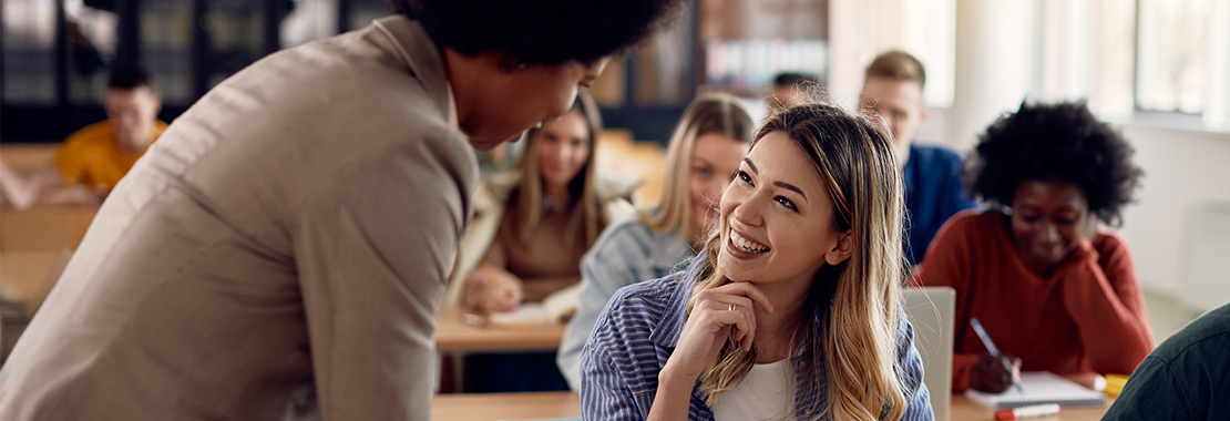 Student interacting with their professor in class.