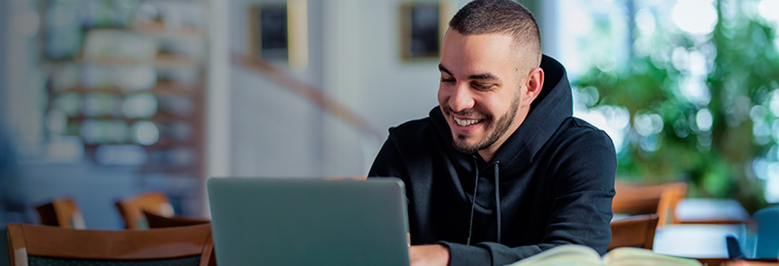 Male student smiles while working on laptop