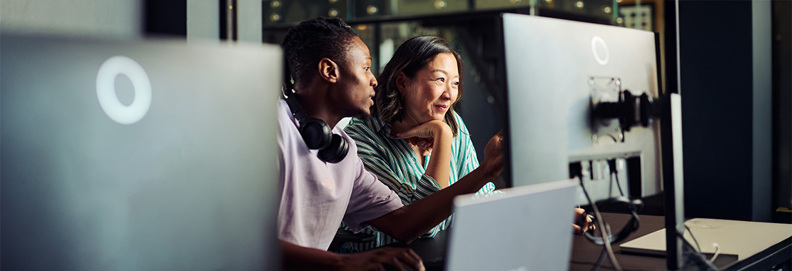 Two individuals look at a computer screen.