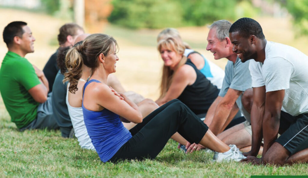 A group of people performing sit ups in an outdoor setting.