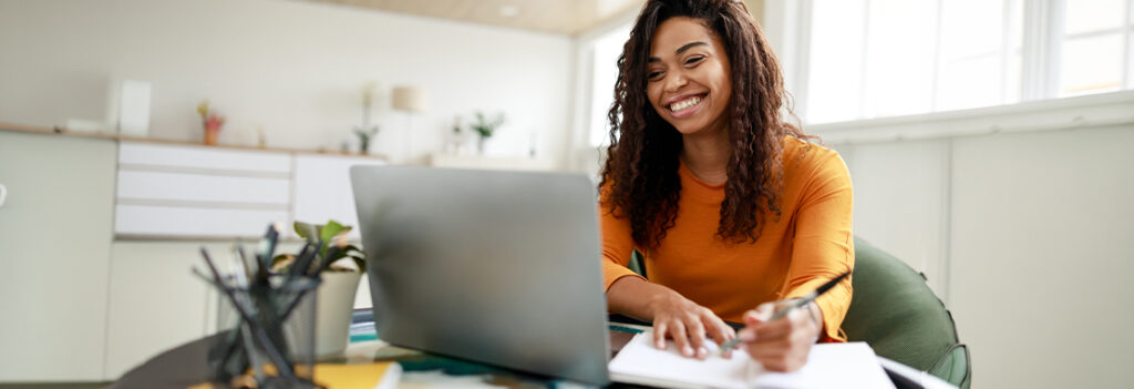 Photograph of a woman studying with a laptop and notebook.